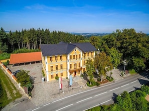 A two-story building with a symmetrical facade, a central entrance, and a paved courtyard.