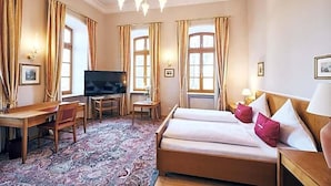 Habitación de hotel con cama, escritorio, televisión y un ventanal grande.