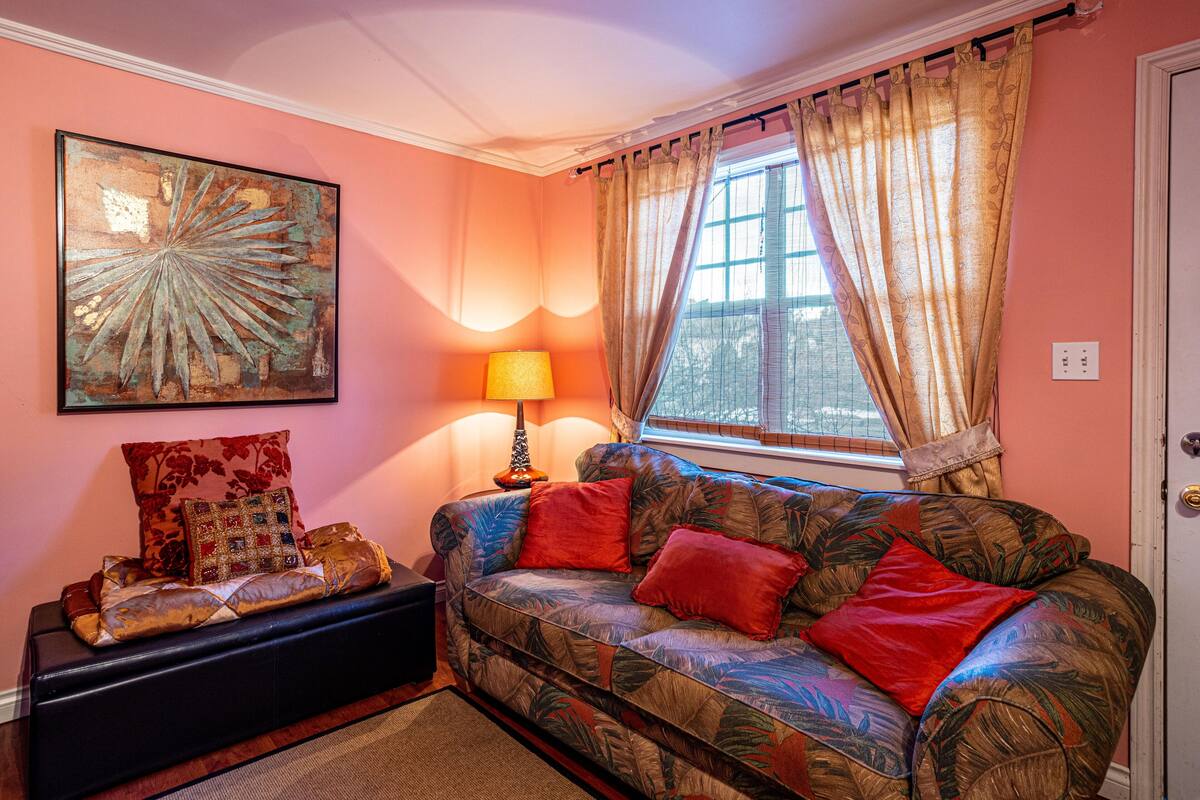 A cozy living room with a patterned sofa, a decorative lamp, and a framed artwork on the wall.