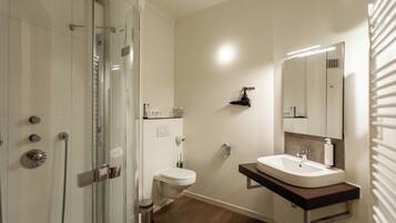 Une salle de bain moderne avec une douche à parois de verre, des toilettes et un meuble-lavabo avec un miroir.