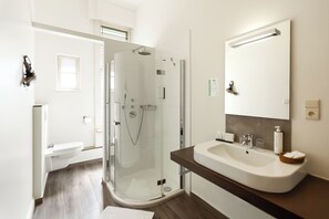 A modern bathroom with a glass-enclosed shower, a white sink, and a large mirror. - Hotel Orion (Ghent)