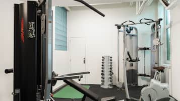 Una palestra con diverse attrezzature per l'allenamento, tra cui una panca, macchinari per pesi e un macchinario cardio.