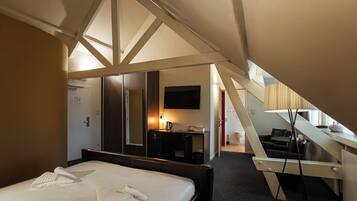 Una habitación de hotel con cama, escritorio, televisor y escalera.