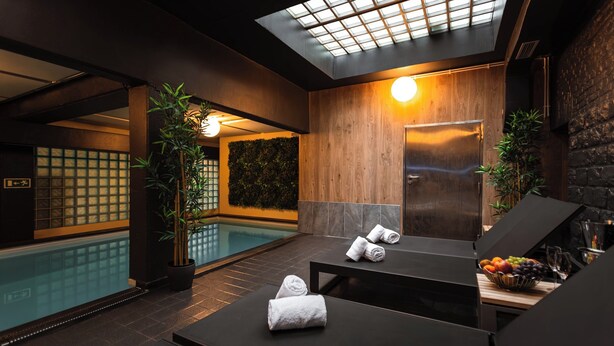 Un espacio de spa con piscina, paredes de madera y una lámpara en el techo.