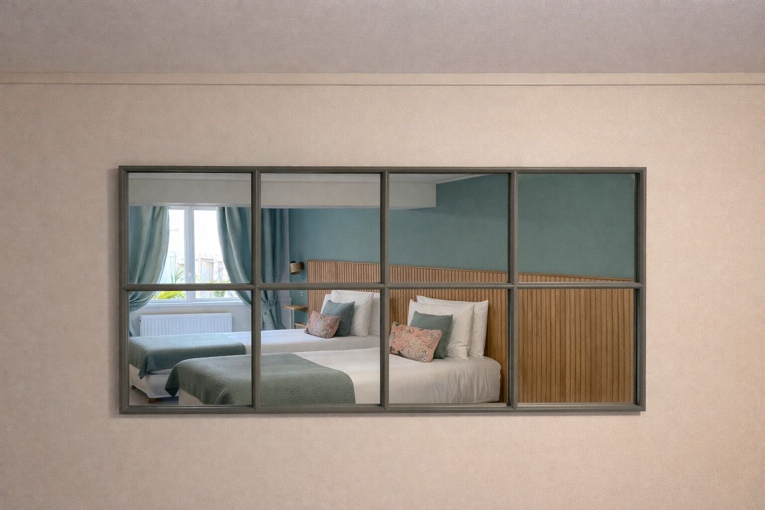 Une chambre avec un grand miroir, deux lits, une fenêtre avec des rideaux et une vue sur l’extérieur.