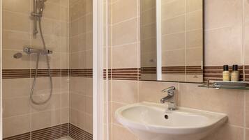 A bathroom with a shower, a sink, and a mirror.