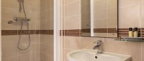 A bathroom with a shower, a sink, and a mirror.