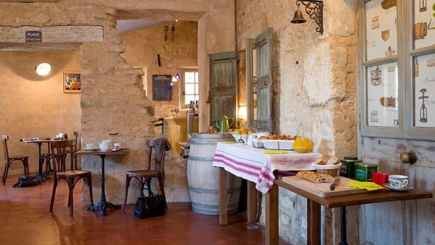 A rustic interior with stone walls, wooden furniture, and a table set with food and drinks. - Hôtel Le Crillon (Murs)
