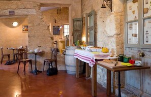 A rustic interior with stone walls, wooden furniture, and a table set with food and drinks. - Hôtel Le Crillon (Murs)