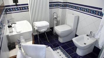 A bathroom with a toilet, bidet, sink, and towel rack.
