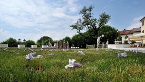 A cemetery with headstones and statues, surrounded by grass and trees. - Villa Carpenada (Belluno)