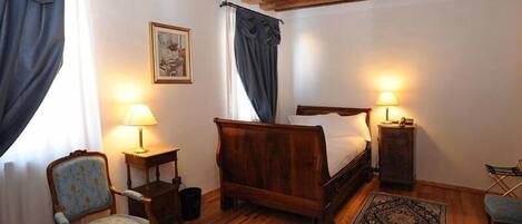 A cozy bedroom with a wooden bed, two bedside lamps, a chair, and a rug.