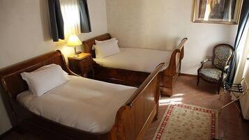 Une pièce avec deux lits en bois, une petite table avec une lampe, un tapis à motifs et une chaise.