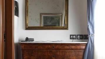 Una habitación con un aparador de madera, un espejo con marco dorado y un tapete estampado en el suelo.