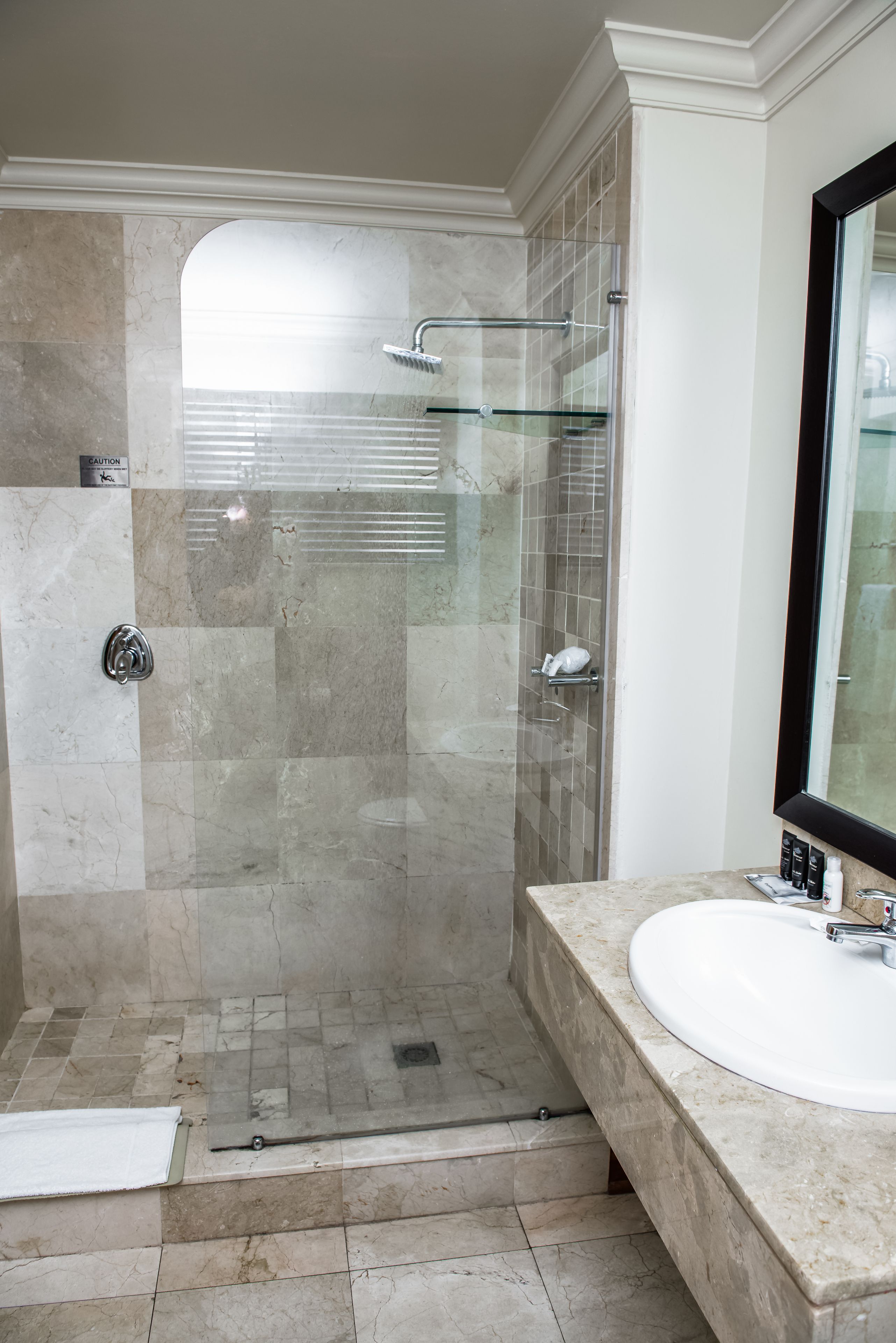 A modern bathroom with a glass-enclosed shower, a white sink, and a large mirror.