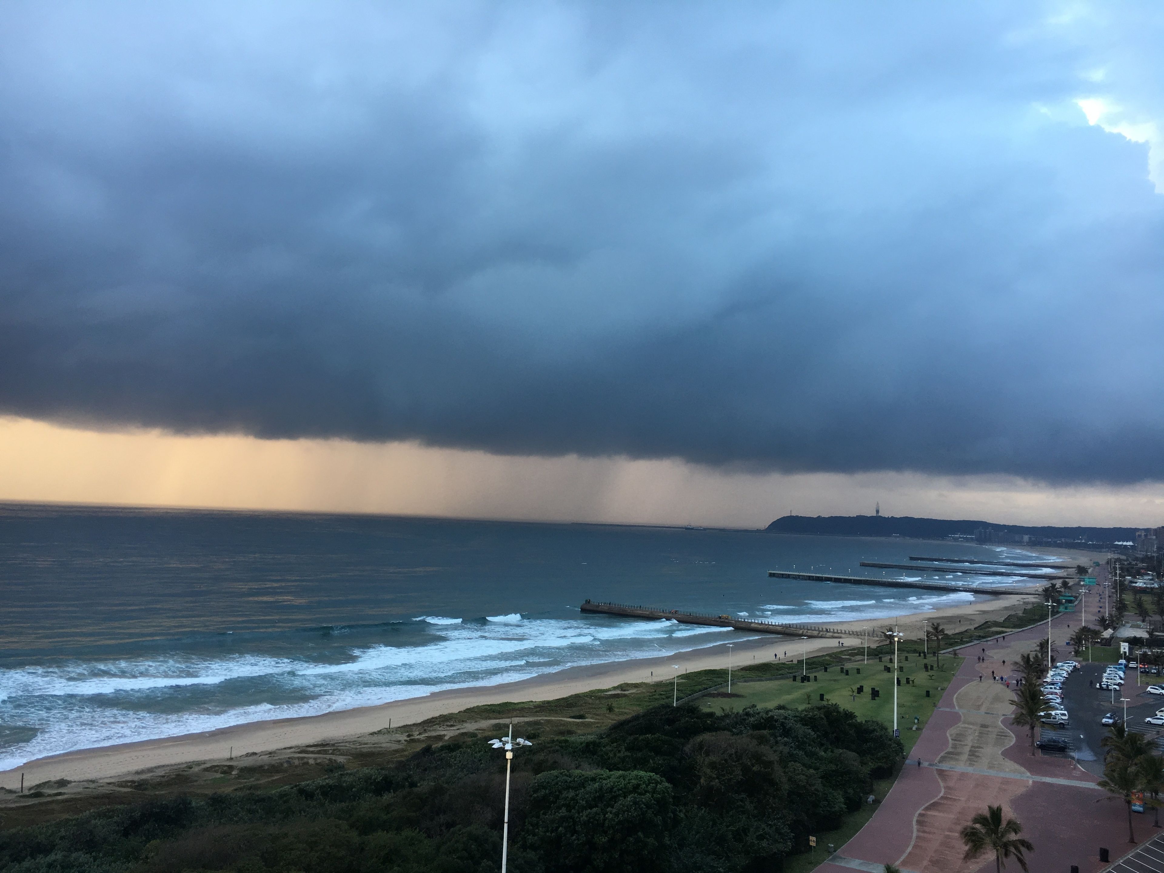 A coastal view with a beach, promenade, and a stormy sky.