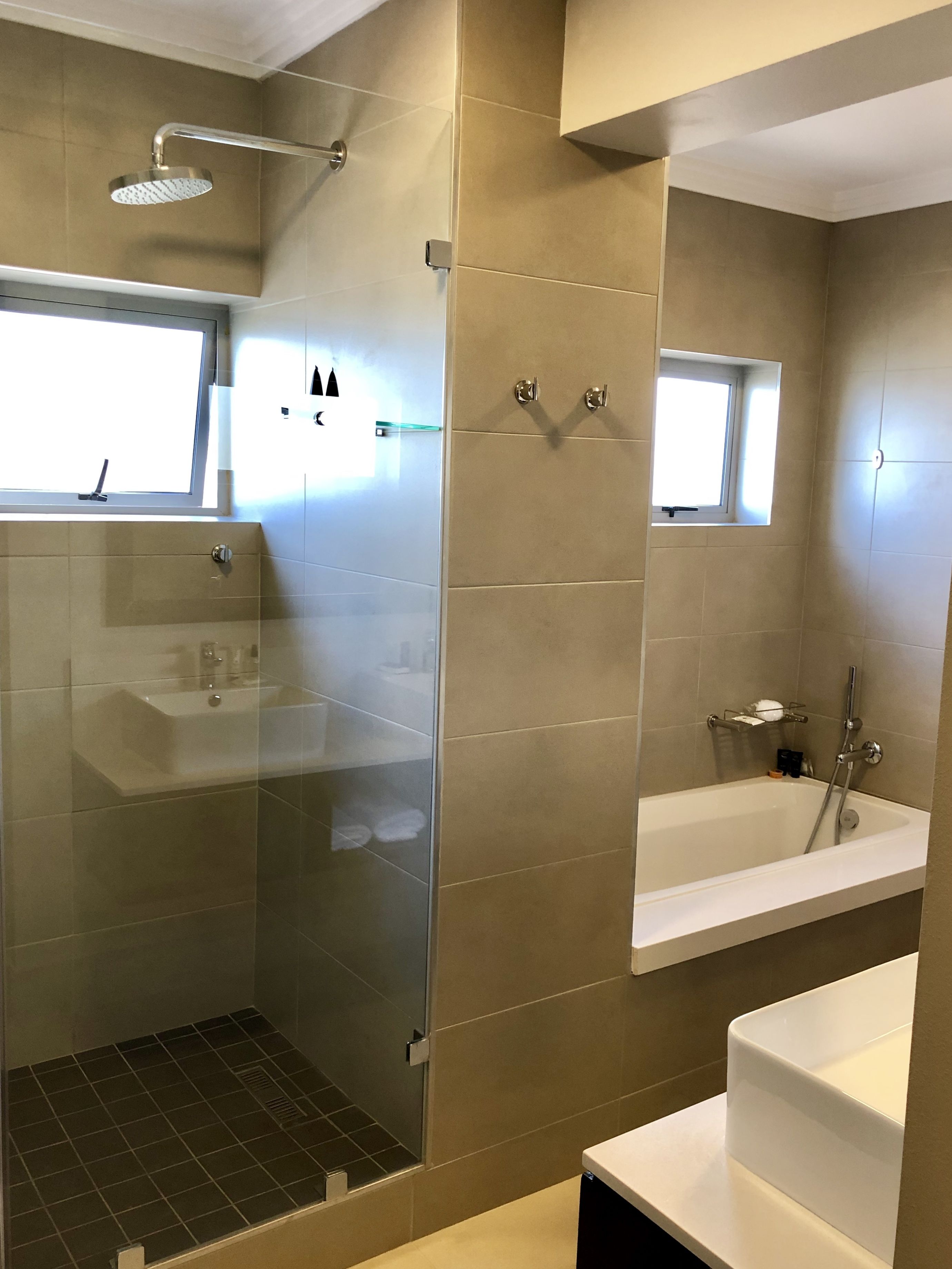 A modern bathroom with a glass-enclosed shower, a freestanding bathtub, and a vanity with a mirror.