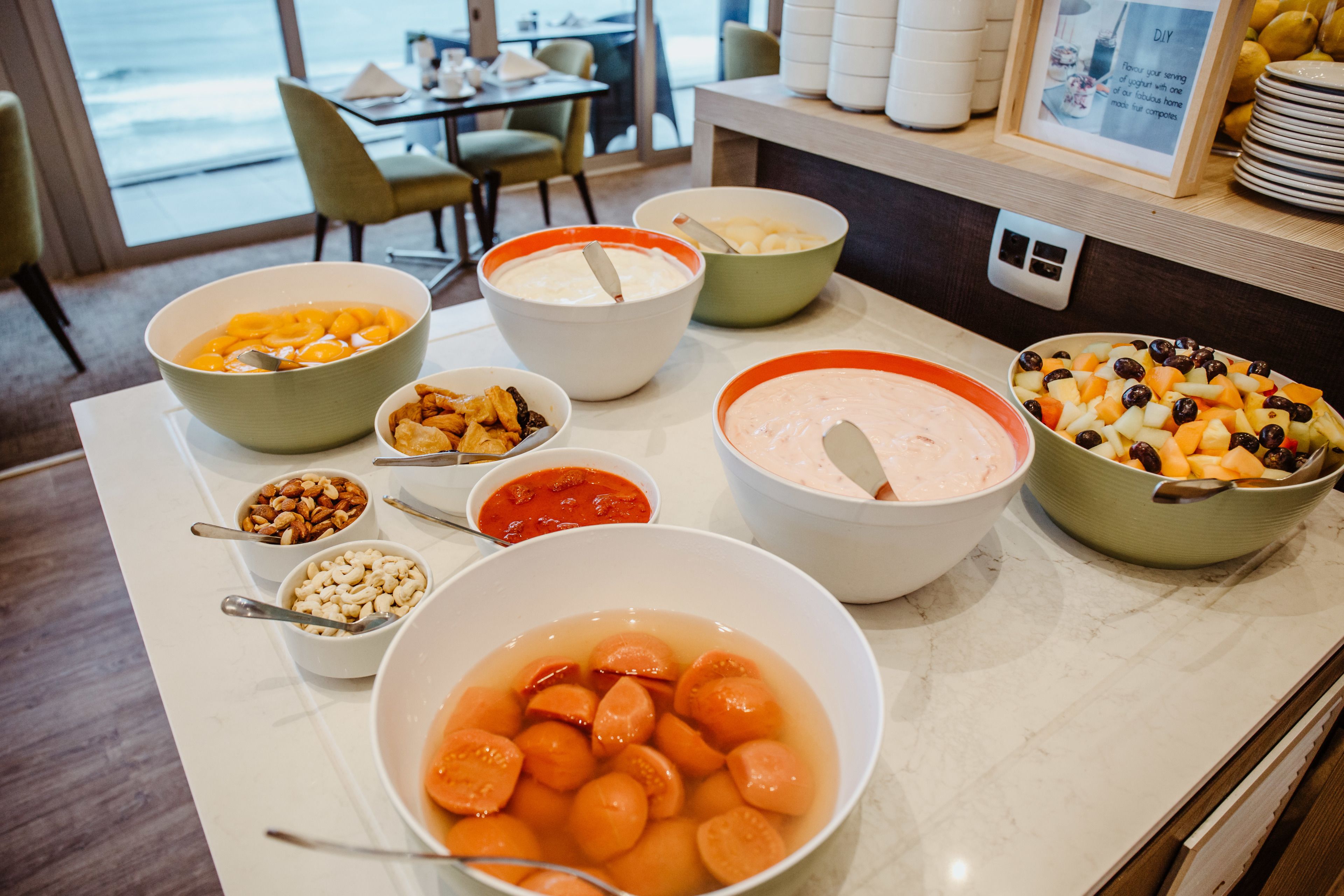 Mesa de buffet com diversos alimentos, incluindo frutas, nozes e patês.