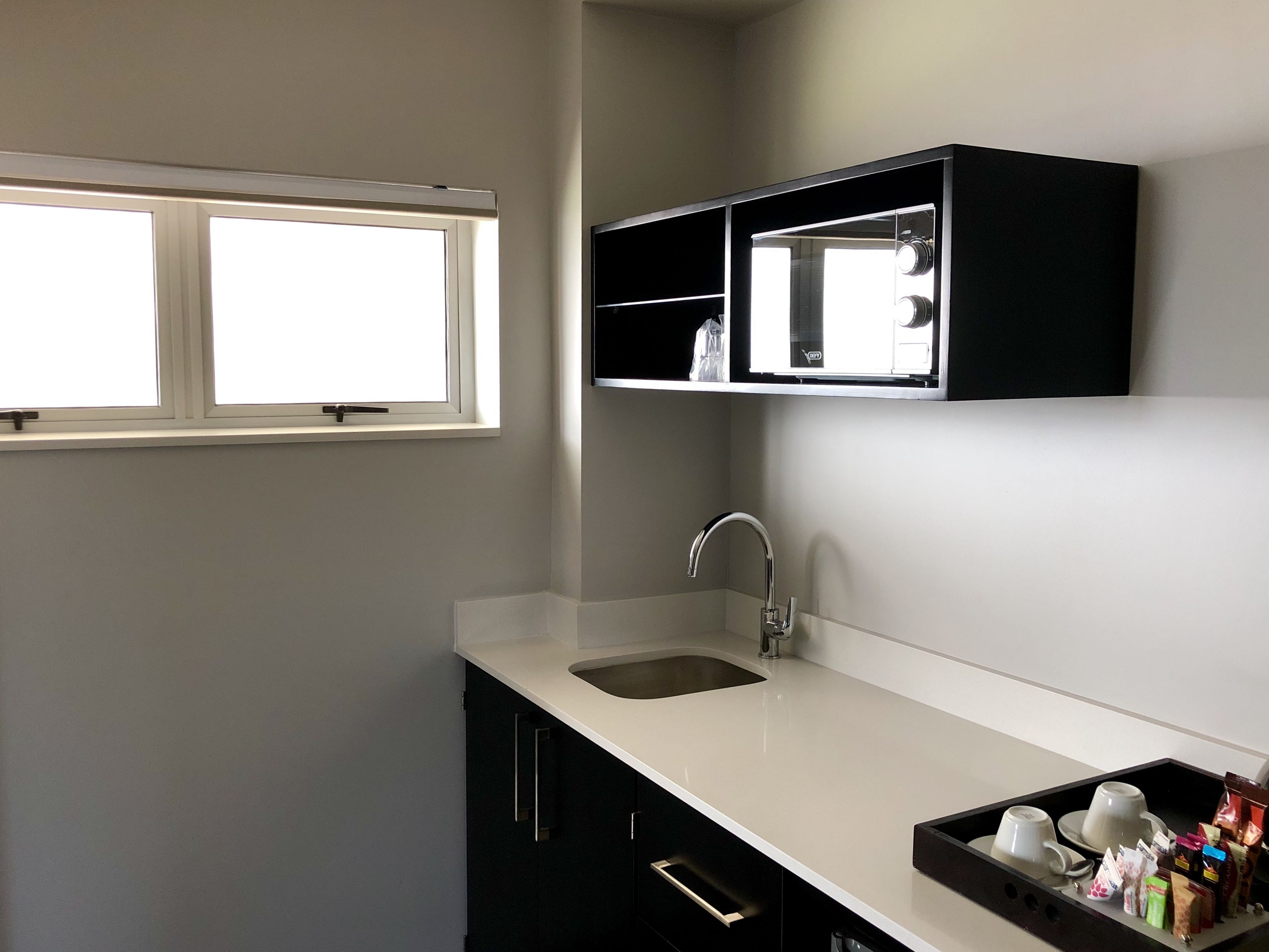 A compact kitchen with a white countertop, a built-in sink, and a window above the sink.