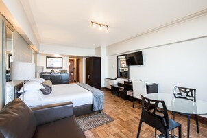 Una habitación de hotel con cama, sofá, escritorio, silla y televisión.