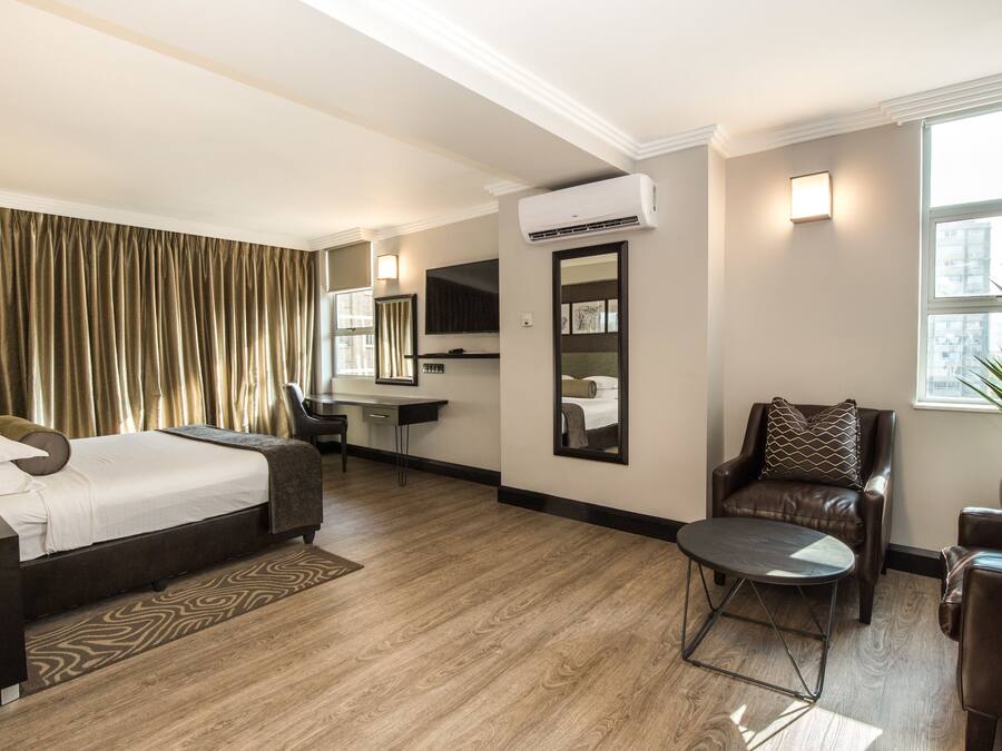 A hotel room with a bed, desk, chair, and a small table.
