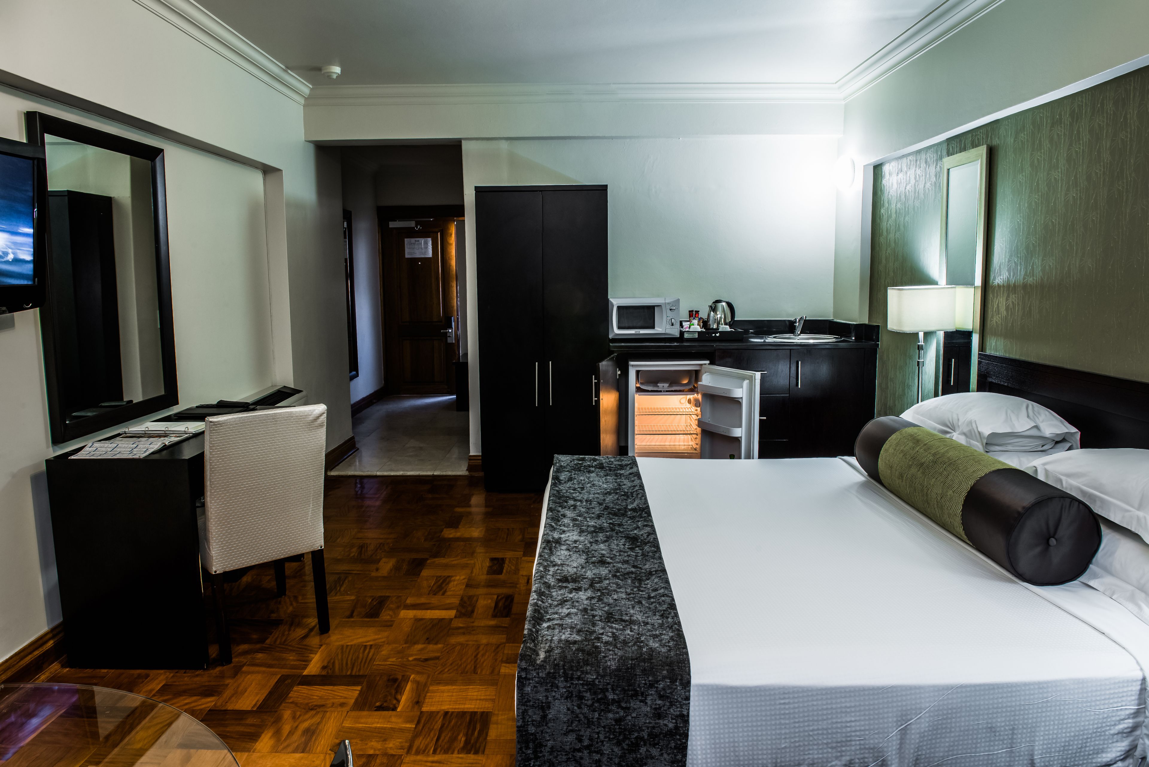 Ein Hotelzimmer mit einem Bett, einem Schreibtisch, einem Sessel, einer Mikrowelle, einem Waschbecken und einem Fernseher.