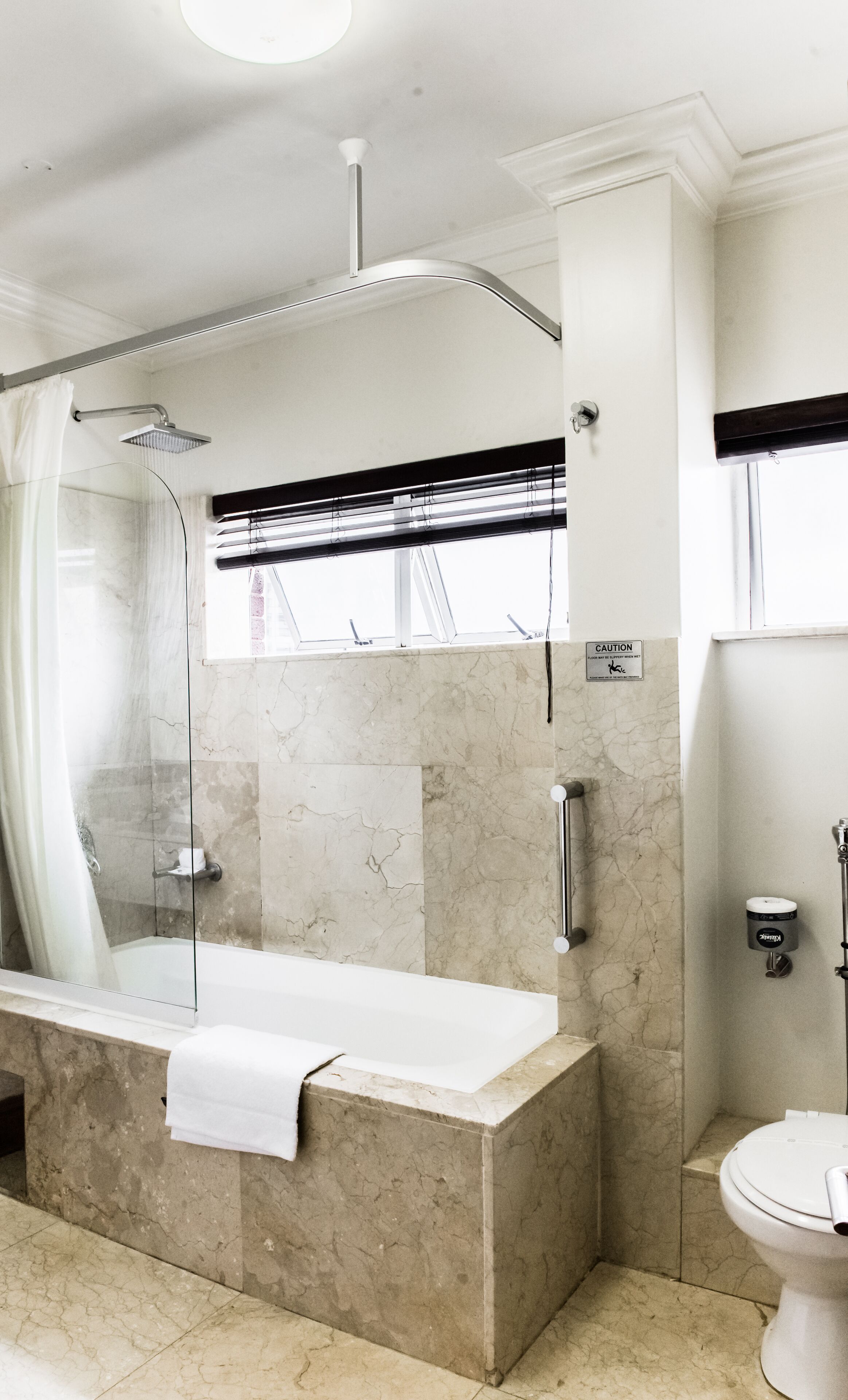 A modern bathroom with a glass-enclosed shower, a freestanding bathtub, and a toilet.