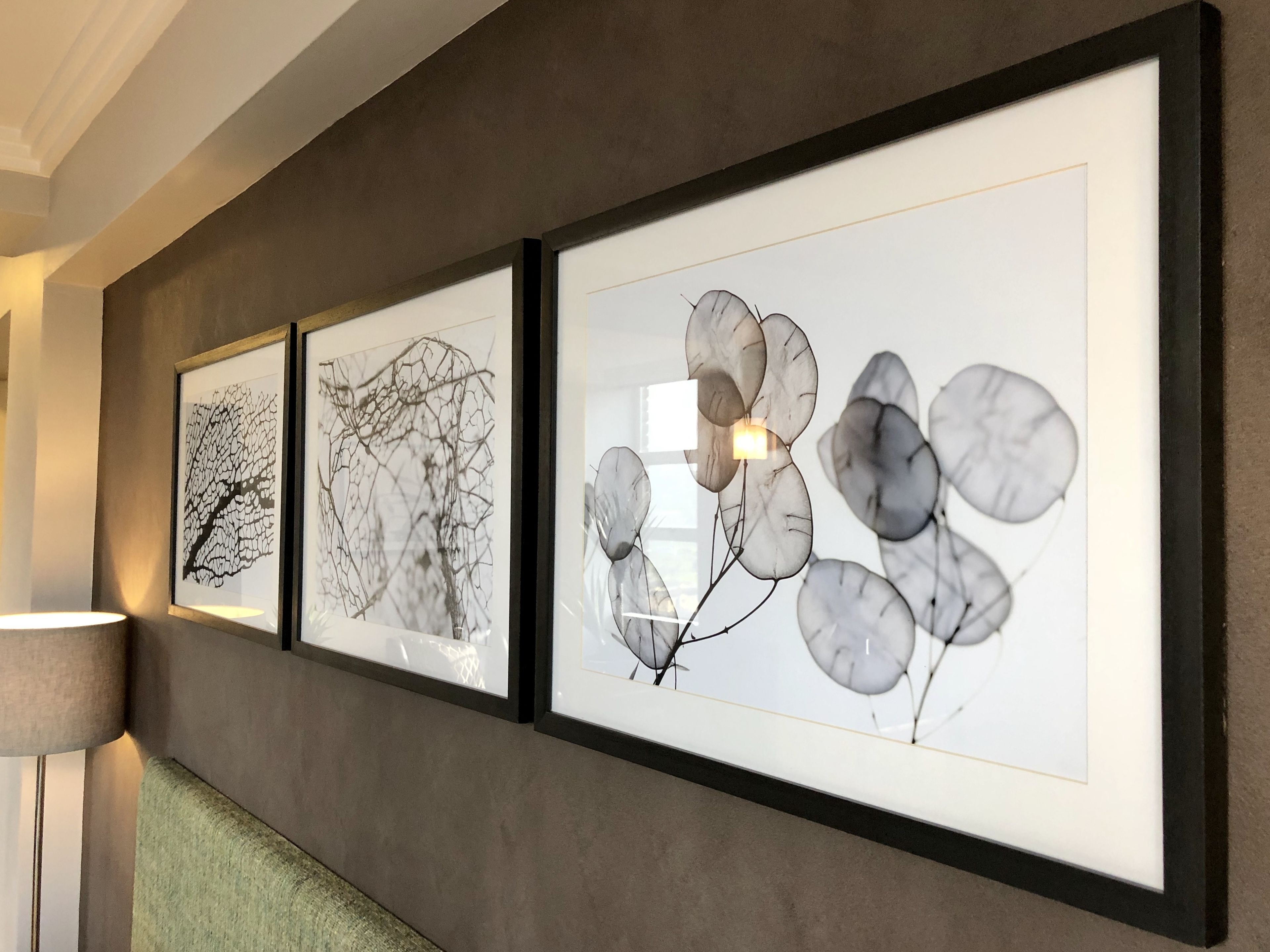 Trois œuvres d’art encadrées sont accrochées au mur dans un couloir.