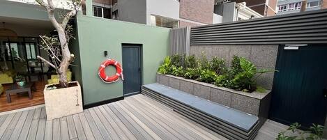 A modern outdoor area with a wooden deck, a small pool, and a planter with green plants.