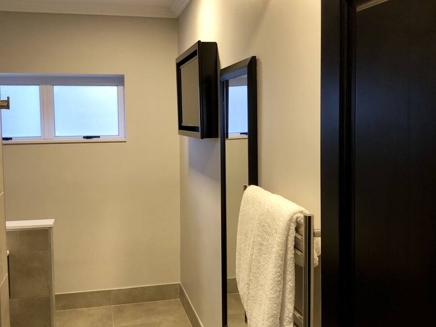 Un baño con espejo, toallero y ventana.