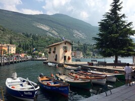 A marina with boats docked, a small building, and a mountainous backdrop.