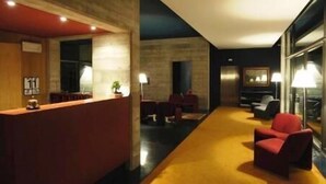 A modern hotel lobby with a reception desk, seating area, and a large window. - Al Caminetto (Nago-Torbole)