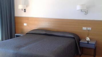 Ein Hotelzimmer mit einem großen Bett, einem Nachttisch mit Lampe und einer Wandleuchte.
