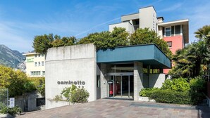 A modern building with a concrete facade and a sign reading "caminetto". - Al Caminetto (Nago-Torbole)