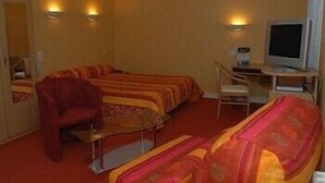 A hotel room with two beds, a desk with a computer, a chair, and a television. - LOGIS HOTEL RESTAURANT DU COMMERCE (Pont-d'Ouilly)