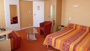 A hotel room with a bed, a chair, a desk, and a mirror. - LOGIS HOTEL RESTAURANT DU COMMERCE (Pont-d'Ouilly)