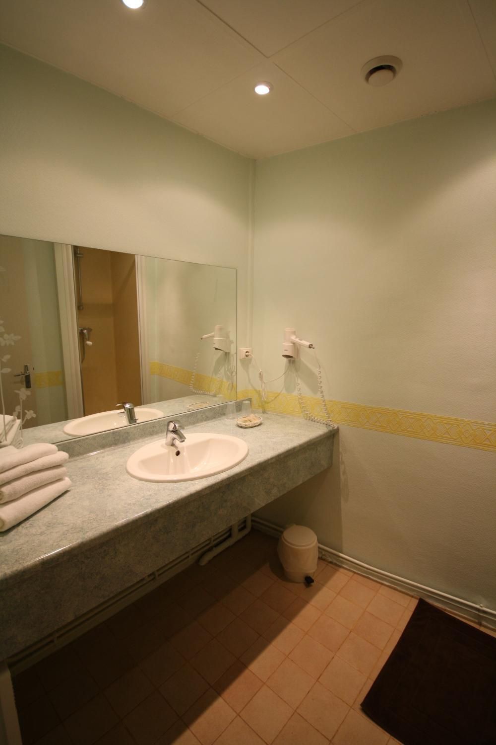 A bathroom with a sink, mirror, and two hair dryers.