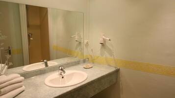 A bathroom with a sink, mirror, and two hair dryers.