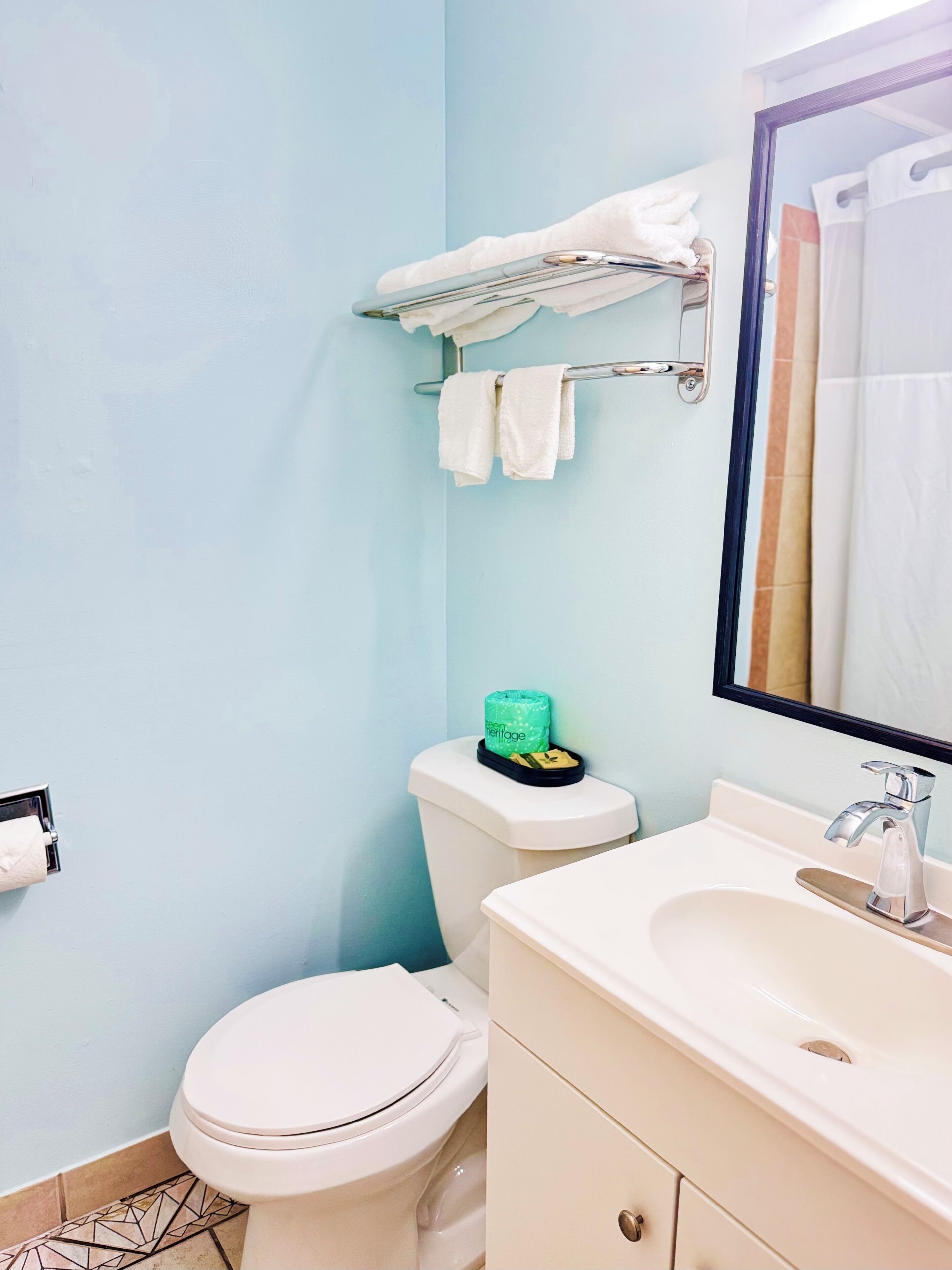A bathroom with a toilet, sink, and mirror.