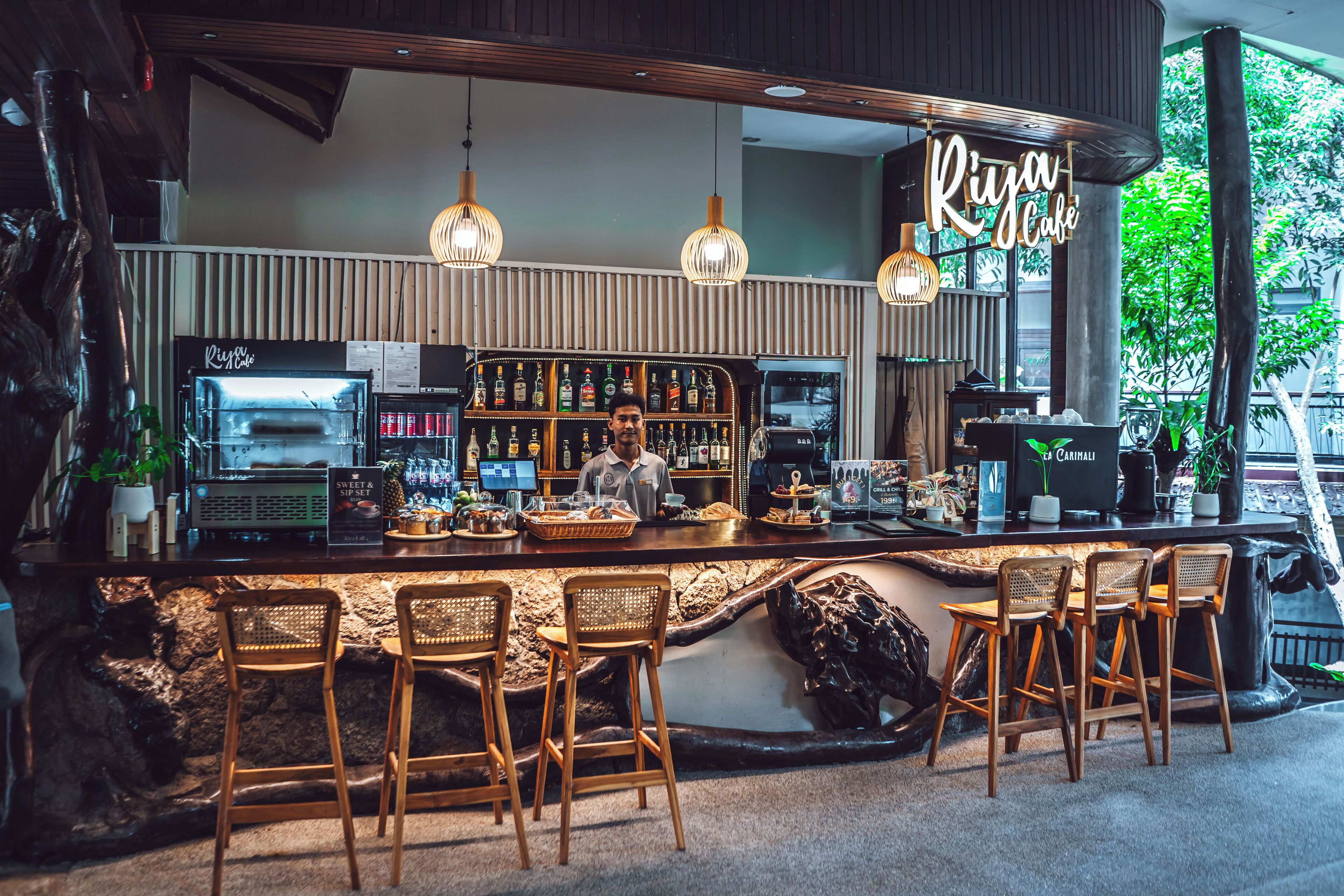 Een bar met een toonbank, barkrukken en een divers aanbod aan flessen en glazen.