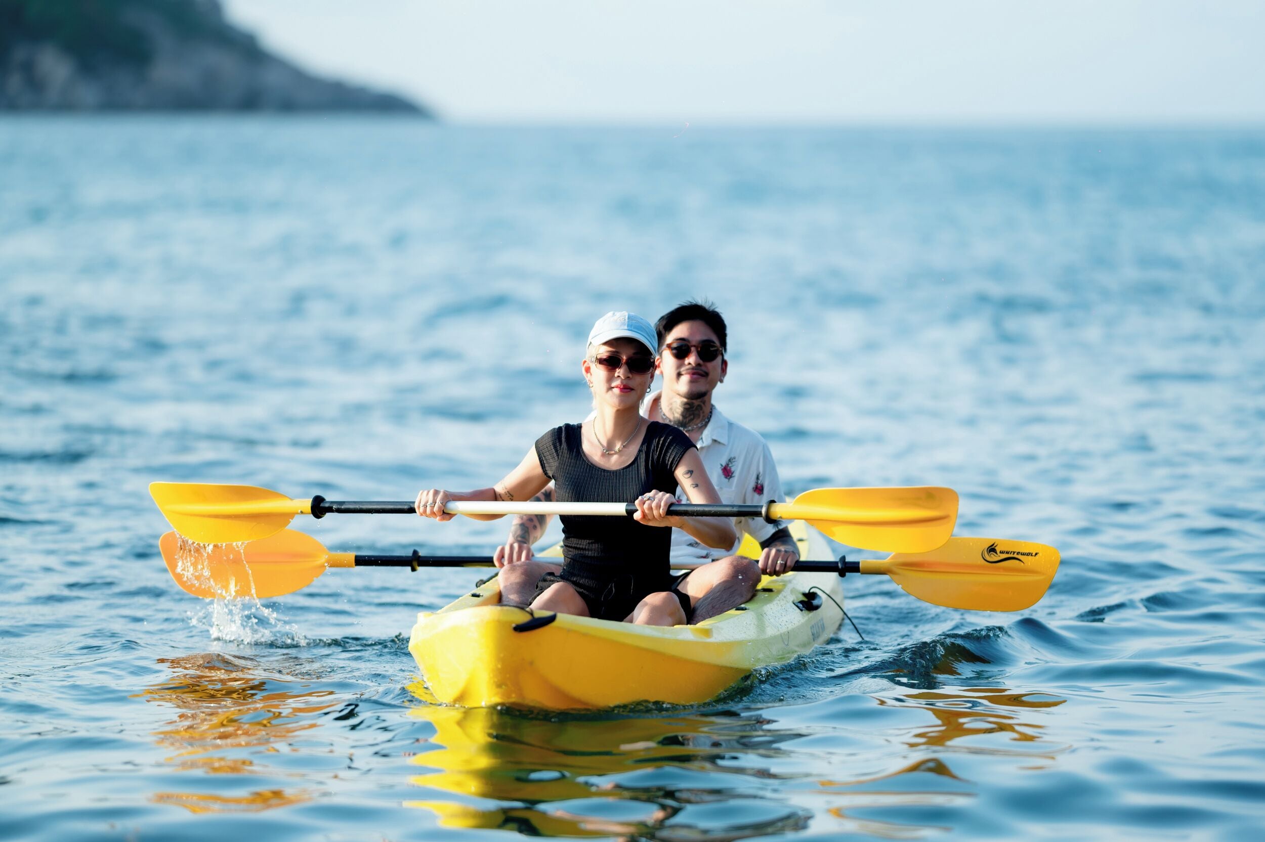 Two people in a yellow kayak on calm water.