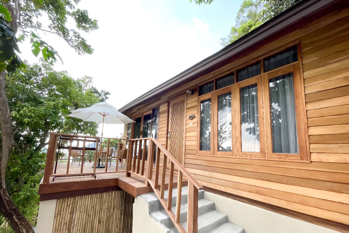 A wooden deck with a staircase leading to a covered area, featuring a number '303' sign.