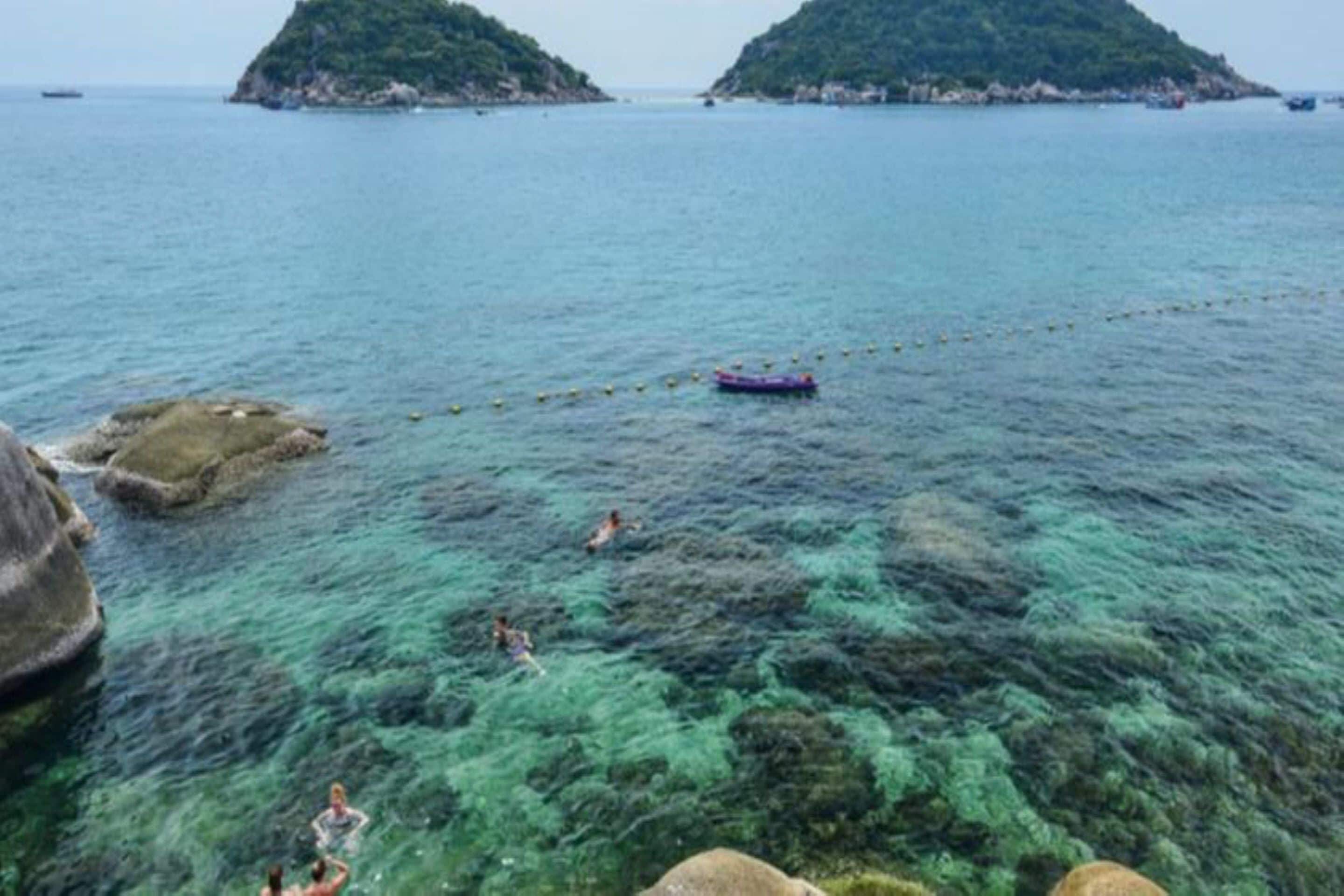 A coastal scene with clear water, rocky formations, and distant islands.