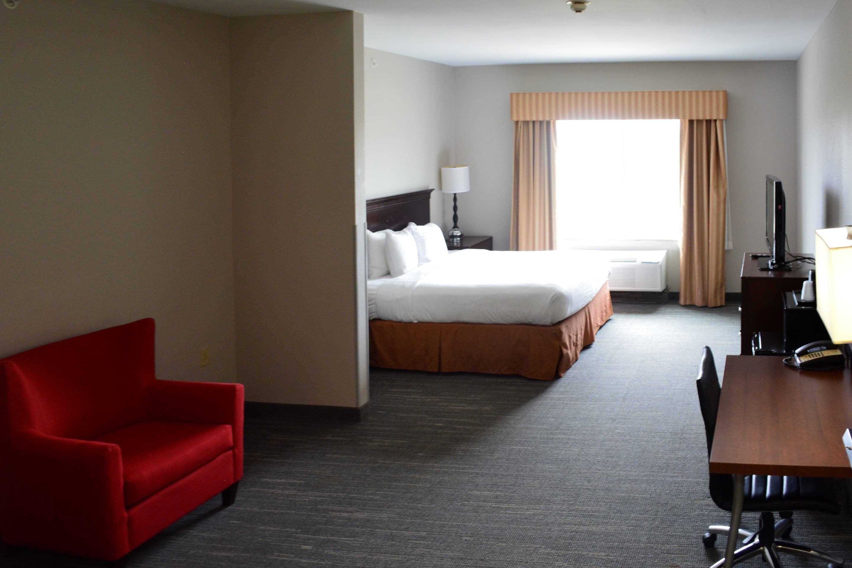 A hotel room with a bed, a desk, a chair, and a television.