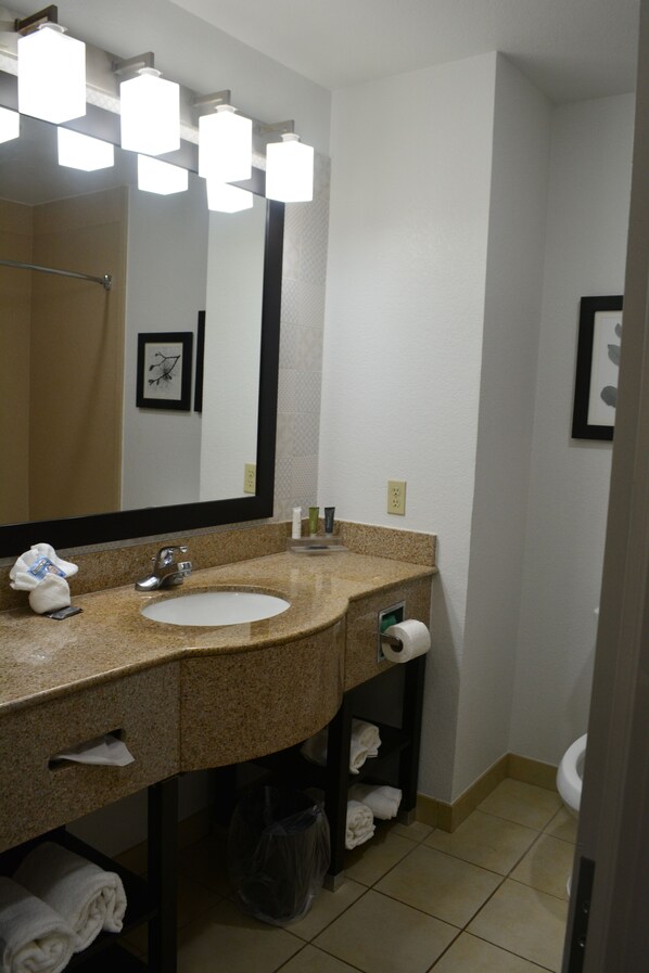 A bathroom with a granite countertop sink, a large mirror, and a toilet. - Country Inn & Suites by Radisson, Oklahoma City - Quail Springs, OK (Oklahoma City)
