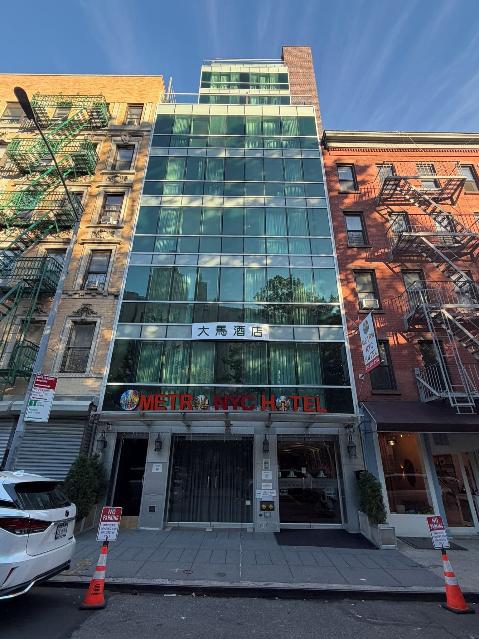Un hôtel à l’architecture moderne, doté d’une grande façade vitrée et d’une enseigne indiquant qu’il s’agit d’un hôtel Metro NYC.