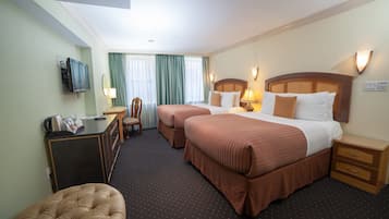 Ein Hotelzimmer mit zwei Betten, einem Schreibtisch, einem Sessel und einem Fernseher.