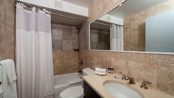 A bathroom with a bathtub, toilet, sink, and a large mirror.