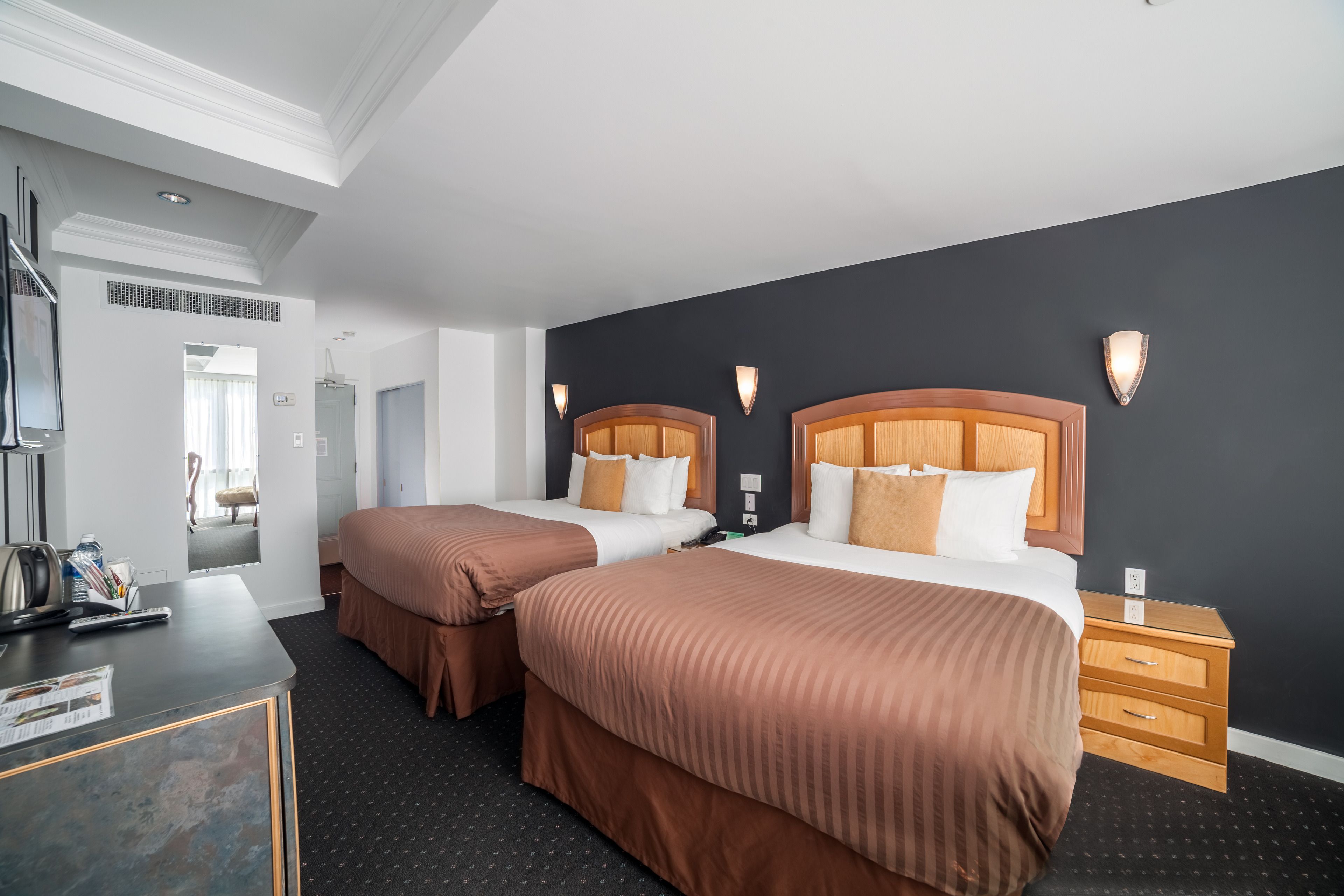 A hotel room with two beds, a desk, and a nightstand.