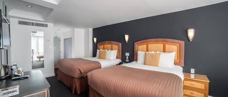 A hotel room with two beds, a desk, and a nightstand.